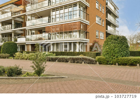 an apartment complex in the suburbs, with brick pavings and green plants on either side of the building stock photo 103727719