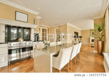 a kitchen and dining area in a house with wood flooring, white chairs and an oven on the wall 103727758