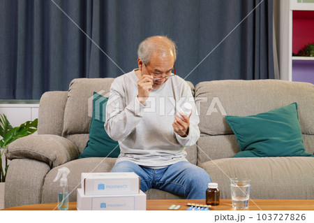 Senior man looking and reading label of medicine at home Senior man looking and reading label of medicine at home 103727826