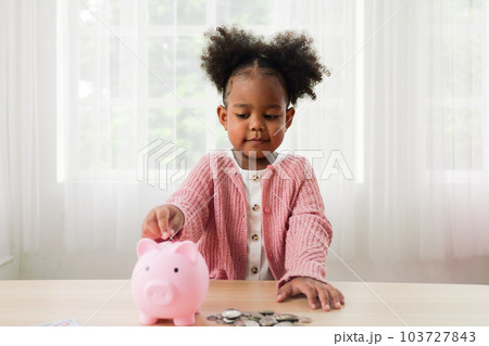 Little girl putting coin of cash into ceramic piggy bank Little girl putting coin of cash into ceramic piggy bank 103727843