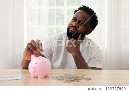 Man putting coin of cash into ceramic piggy bank 103727909