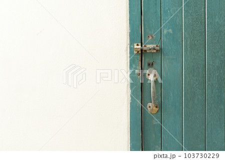 The Closed padlock hangs on the green color wooden door and wall. The Closed padlock hangs on the green color wooden door and wall. 103730229