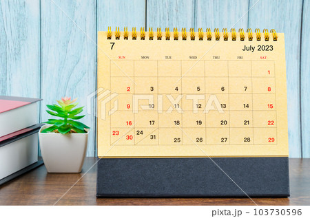 July 2023 Monthly desk calendar for the organizer to plan 2023 year with the books on wooden table. 103730596