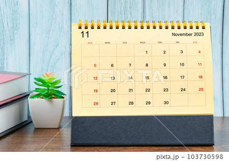 The November 2023 Monthly desk calendar for 2023 year with the books on blue wooden background. The November 2023 Monthly desk calendar for 2023 year with the books on blue wooden background. 103730598