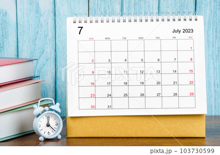 The July 2023 Monthly desk calendar for the organizer to plan 2023 year with alarm clock and books on wooden table. The July 2023 Monthly desk calendar for the organizer to plan 2023 year with alarm clock and books on wooden table. 103730599