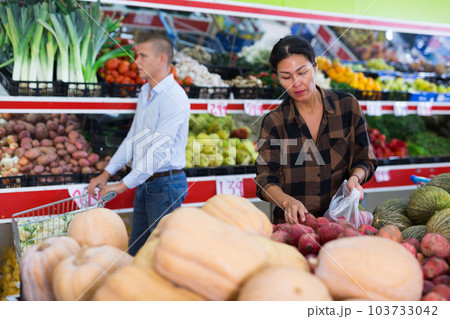 Asian woman choosing pomegranates on counter in greengrocery 103733042