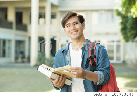 Student standing outdoor and holding books. 103733949