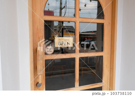 Wooden sign hangs welcome open coffee shop door. 103738110