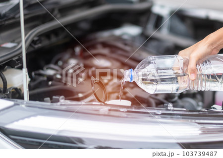 woman hand filing pure water in windscreen washer tank car. Self Maintenance, repair and problem concept woman hand filing pure water in windscreen washer tank car. Self Maintenance, repair and problem concept 103739487