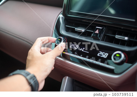 man hand adjusting temperature the air flowing during driving car on the road, air conditioner cooling system inside the car. Adjust, temperature and transport concept 103739511