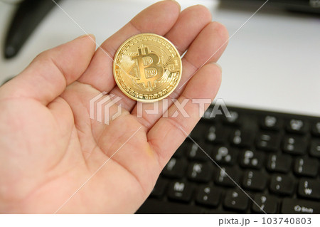 Hand hold gold bitcoin cryptocurrency on grey background. Physical bit coin. Digital currency 103740803
