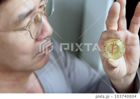 Hand hold gold bitcoin cryptocurrency on grey background. Physical bit coin. Digital currency Hand hold gold bitcoin cryptocurrency on grey background. Physical bit coin. Digital currency 103740804