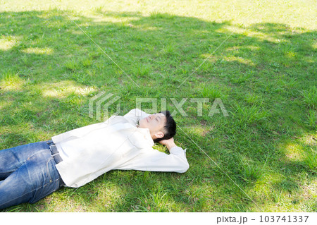 芝生に寝転ぶ男性の写真 103741337