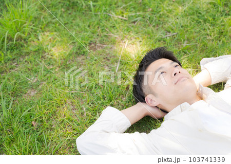 芝生に寝転ぶ男性の写真 103741339
