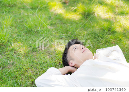 芝生に寝転ぶ男性の写真 芝生に寝転ぶ男性の写真 103741340