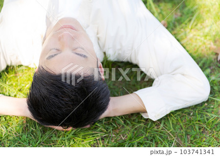 芝生に寝転ぶ男性の写真 103741341