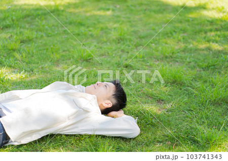 芝生に寝転ぶ男性の写真 103741343