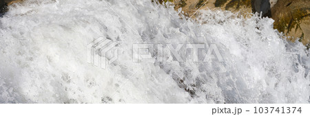 Bubbling river waterfall stream with white foam flows over stones 103741374