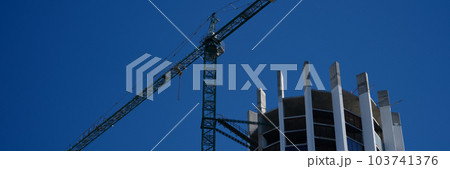 Tower crane in action construction of a new round shaped multi-storey building Tower crane in action construction of a new round shaped multi-storey building 103741376