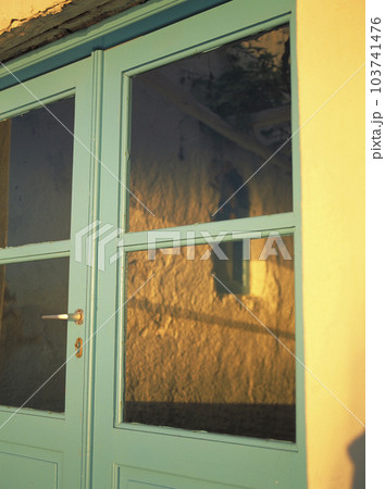 パステルグリーンの扉を照らす夕暮れの光 103741476