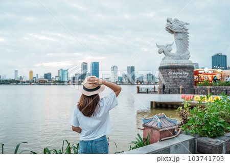 Woman Traveler visiting in Da Nang. Tourist sightseeing the river view with Carp Dragon Statue or Ca Chep Hoa Rong.Landmark and popular. Da Nang, Vietnam, 13 November 2022 Woman Traveler visiting in Da Nang. Tourist sightseeing the river view with Carp Dragon Statue or Ca Chep Hoa Rong.Landmark and popular. Da Nang, Vietnam, 13 November 2022 103741703