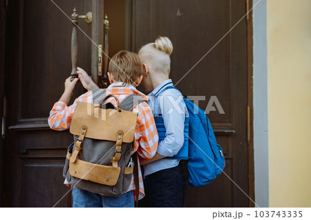 children entering school opening big wooden door. Boys with backpacks by school on sunny day children entering school opening big wooden door. Boys with backpacks by school on sunny day 103743335
