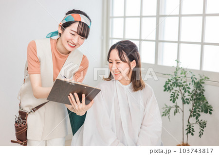 美容室・ヘアサロンでヘアスタイル・髪型を相談する客の女性とカウンセリングする美容師 美容室・ヘアサロンでヘアスタイル・髪型を相談する客の女性とカウンセリングする美容師 103743817