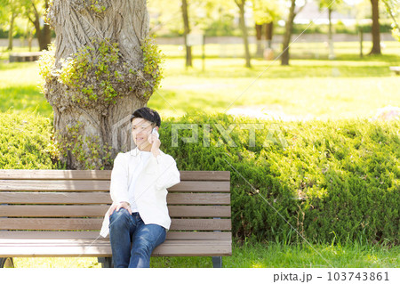 公園のベンチに座る男性の写真の写真素材 [103743861] - PIXTA