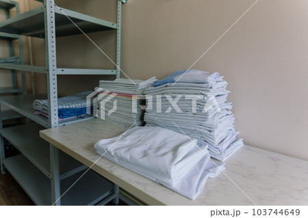Linens piled neatly on shelves. There are folded bed sheets, towels, wash clothes 103744649