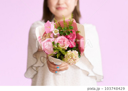 花束を手渡す笑顔の若い女性 花束を手渡す笑顔の若い女性 103748429