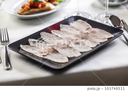 Thinly sliced veal with a tuna salsa served on a black rectangular plate Thinly sliced veal with a tuna salsa served on a black rectangular plate 103748511