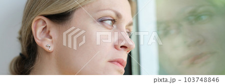 Sad woman is bored and looks out window 103748846