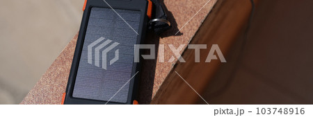 Solar power bank for charging mobile phone lying under rays of sun closeup 103748916