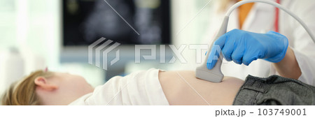 Doctor conducting abdominal ultrasound examination of internal organs of child in clinic closeup 103749001