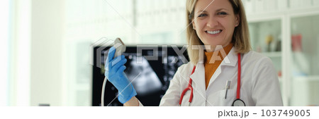 Smiling woman doctor holding ultrasound probe in her hands in clinic 103749005