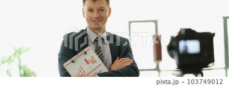 Male business coach standing in front of camera with documents in hands 103749012