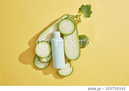 Against beige background, unbranded bottle displayed with winter melon slices. Winter melon (Benincasa hispida) remains rich in fiber and provides small amounts of various nutrients 103750142
