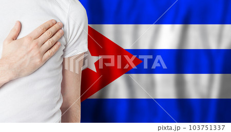 Cuban person with hand on heart on the background of Cuba flag. Patriotism, country 103751337