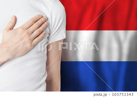 Dutch person with hand on heart on the background of Netherlands flag. Patriotism, country Dutch person with hand on heart on the background of Netherlands flag. Patriotism, country 103751343