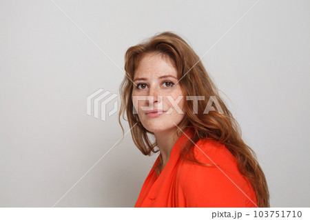 Portrait of attractive woman with ginger wavy hair and freckles looking at camera Portrait of attractive woman with ginger wavy hair and freckles looking at camera 103751710