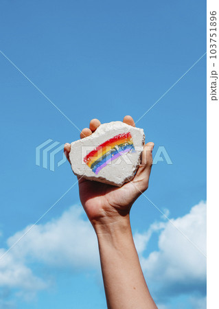 holds rock with a rainbow flag in his hand holds rock with a rainbow flag in his hand 103751896