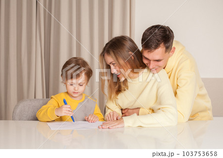 Adorable smiling family, parents in yellow clothes with their son painting 103753658
