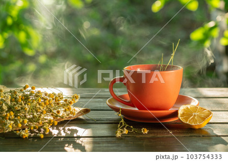 Orange mug with a healing drink made from dry herbs. Tea with chamomile and lemon is used in folk medicine for colds. 103754333