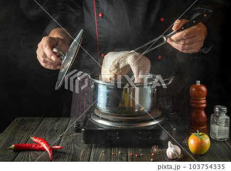 Cooking delicious broth from chicken legs and vegetables by the hands of a chef in the kitchen of a restaurant or hotel 103754335