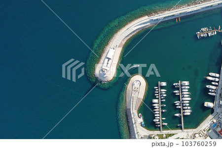 Aerial view of luxury sailing yachts and boats in yacht club near wooden piers. Top view of european city. Large boat parking near sea coast. Road to the lighthouse. Yachting in summer concept. 103760259
