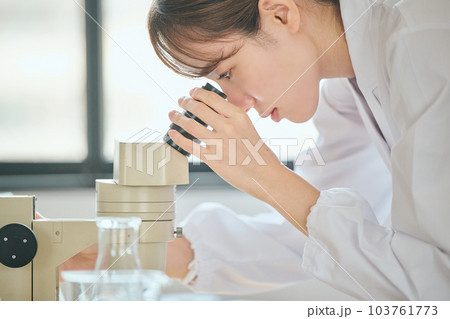 顕微鏡を覗く白衣の若い女性 顕微鏡を覗く白衣の若い女性 103761773
