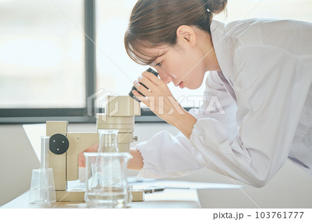 顕微鏡を覗く白衣の若い女性 顕微鏡を覗く白衣の若い女性 103761777