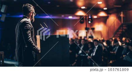 Speaker giving a talk on corporate business conference. Unrecognizable people in audience at conference hall. Business and Entrepreneurship event. 103761809