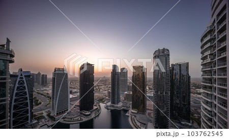 Tall residential buildings at JLT aerial night to day timelapse, part of the Dubai multi commodities centre mixed-use district. 103762545