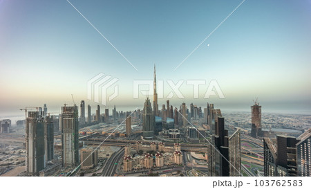 Aerial view of tallest towers in Dubai Downtown skyline and highway night to day timelapse. Aerial view of tallest towers in Dubai Downtown skyline and highway night to day timelapse. 103762583